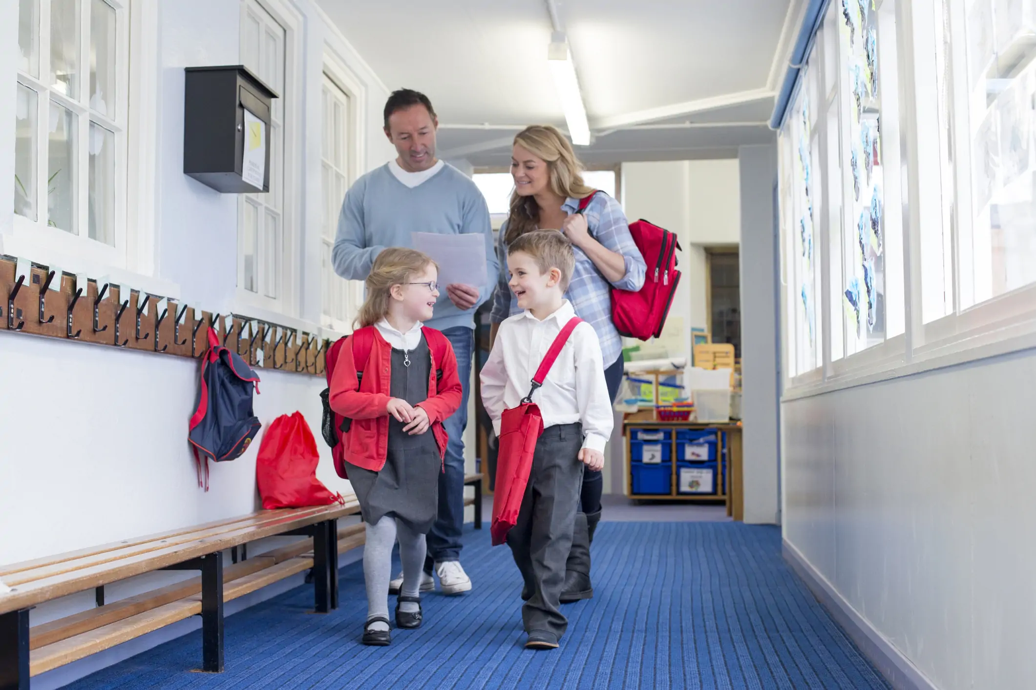 Parents walking with two children through school while smiling.