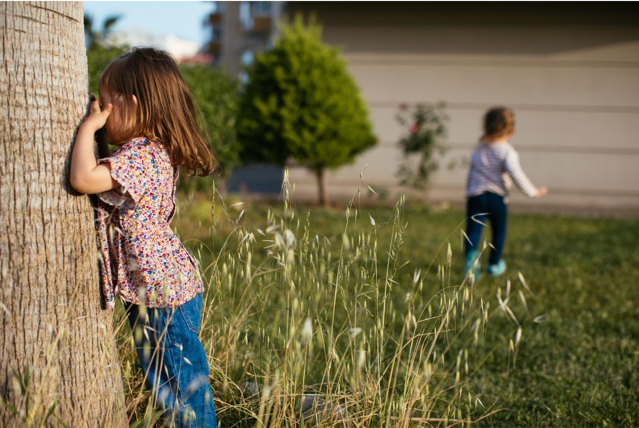 Two young children play hide and seek.