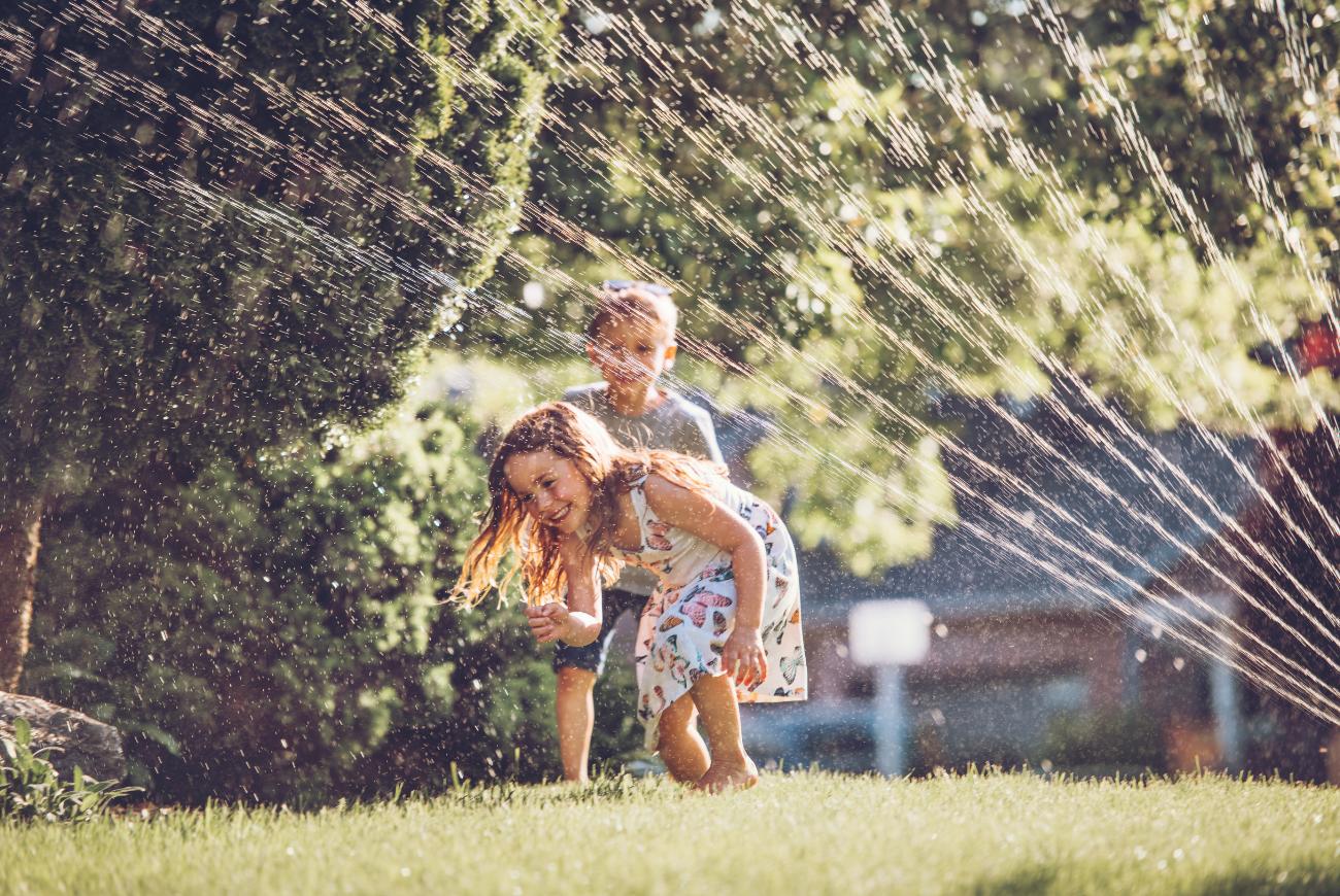 Two children running from sprinklers.