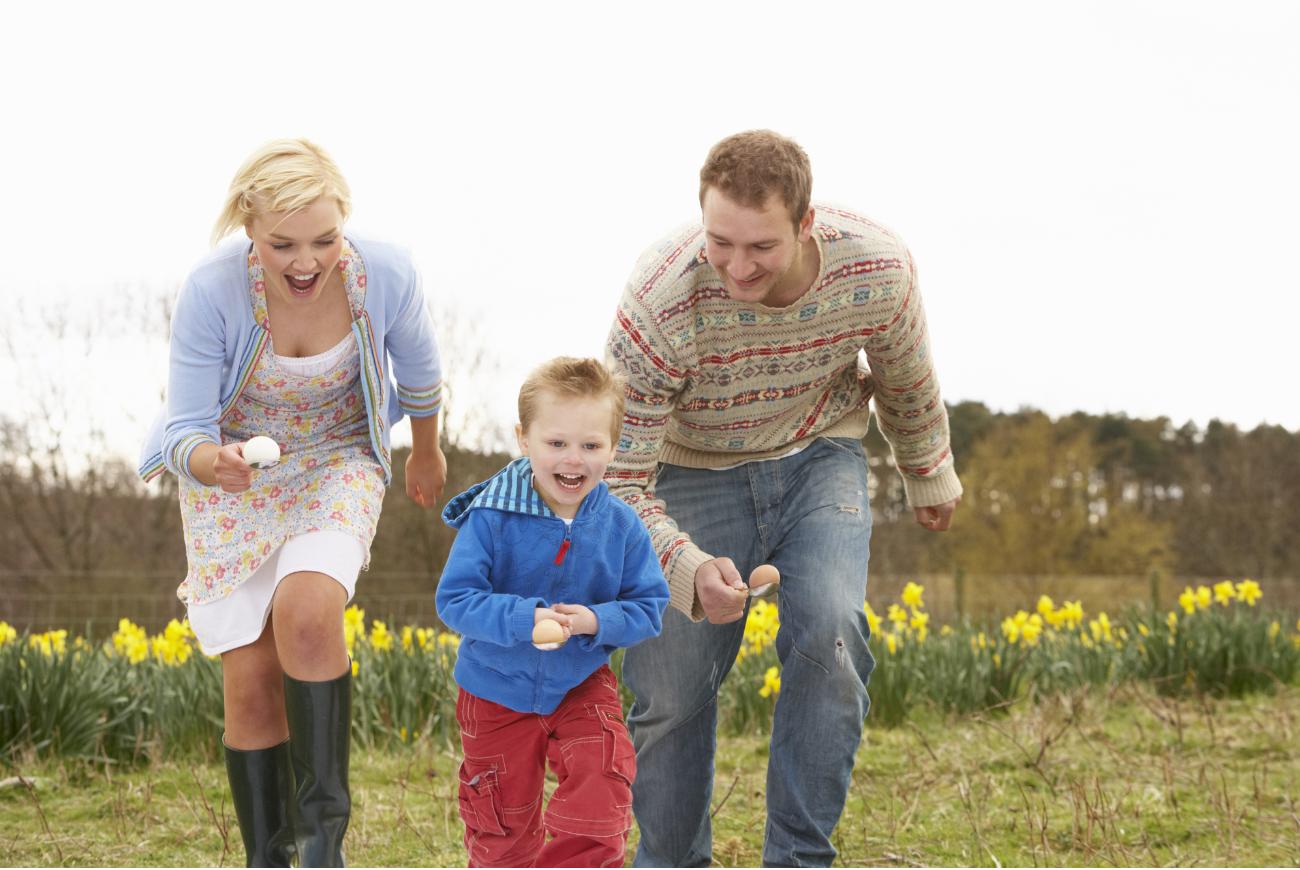 Two parents and a child race together with an egg and spoon.