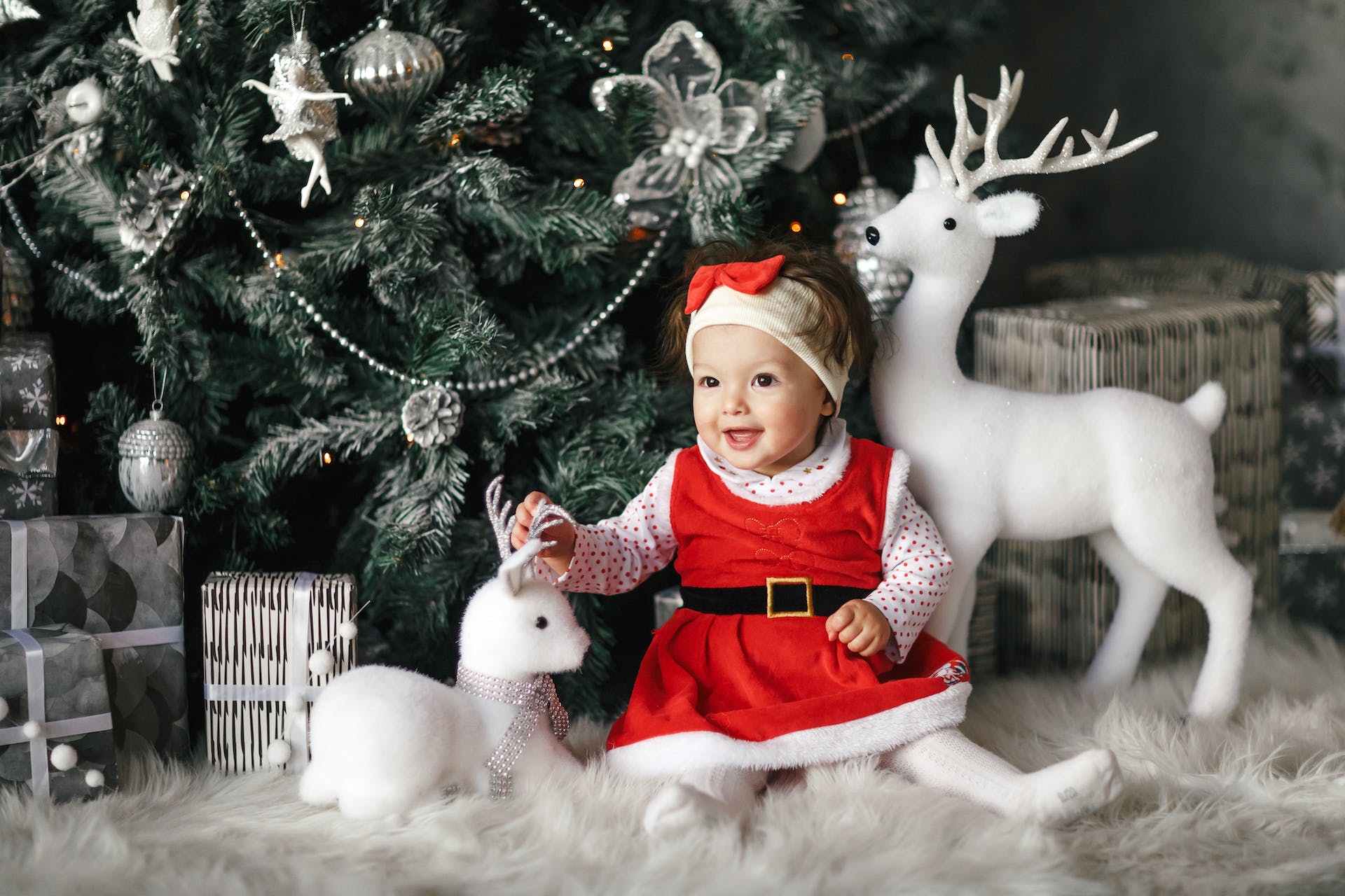 Baby sat by Christmas tree.