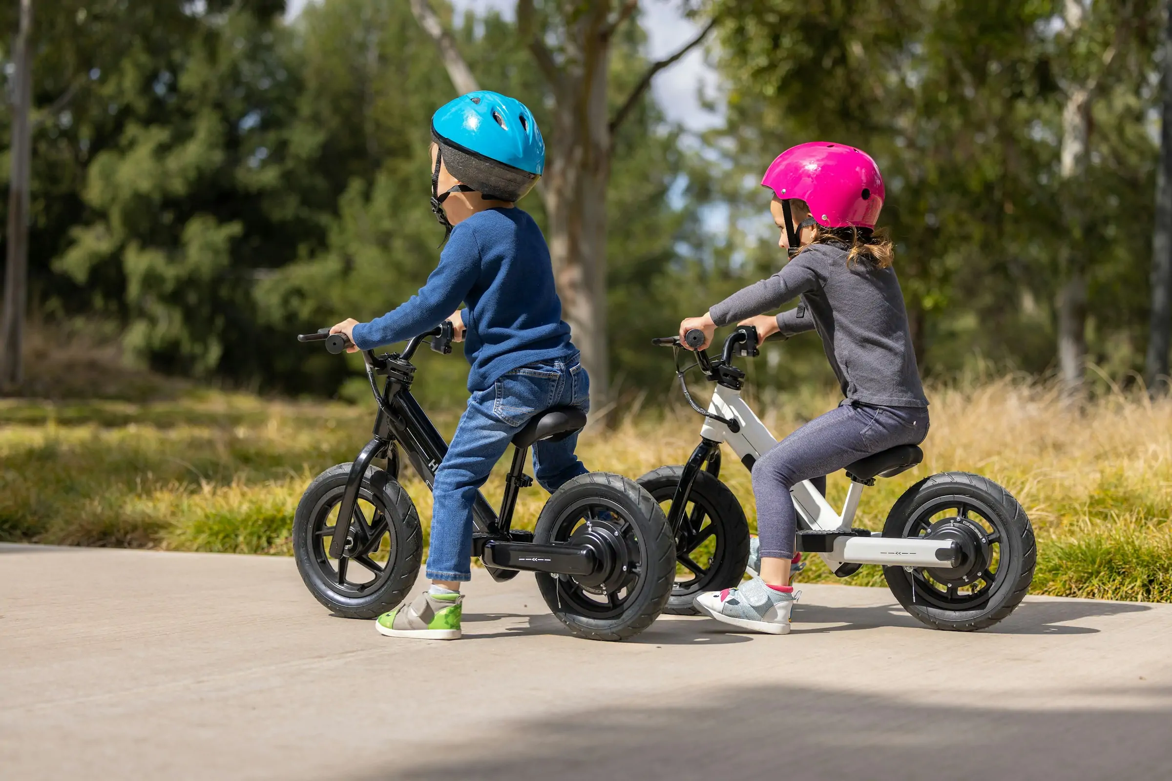 Two young children cycle together on their own bikes.