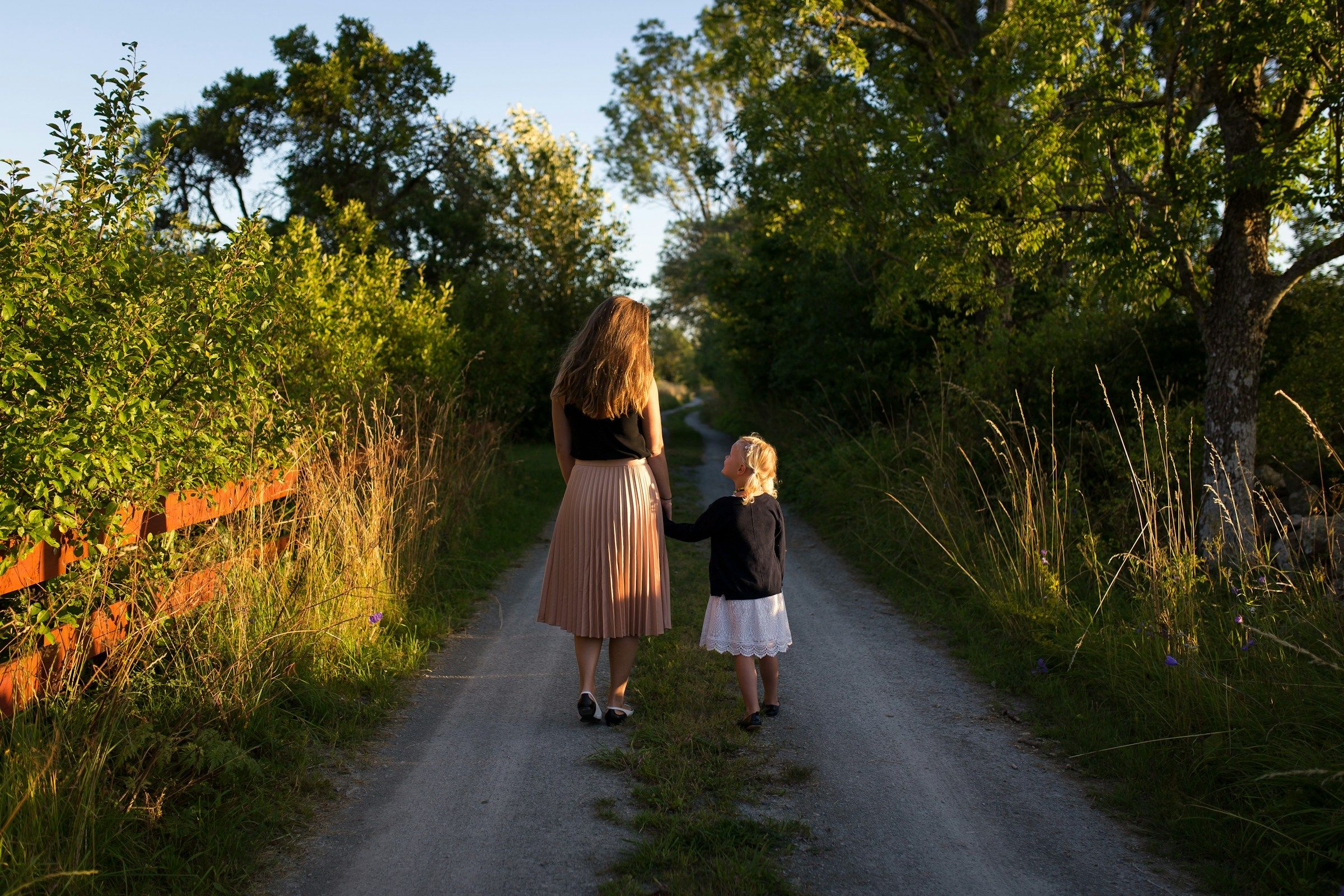 Mother and daughter walk through a pathway.