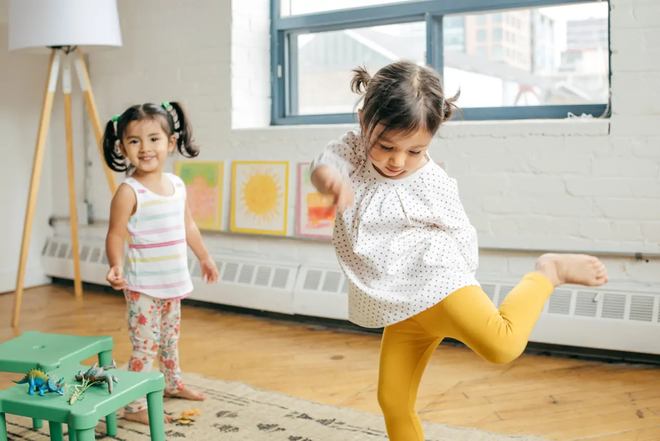 Two small children dancing in a modern living room