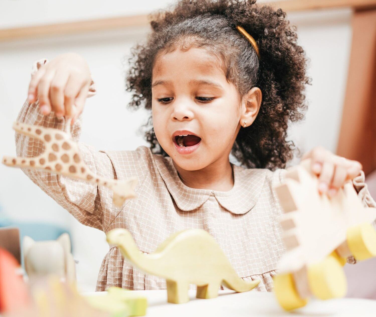 little girl playing with wooden animals