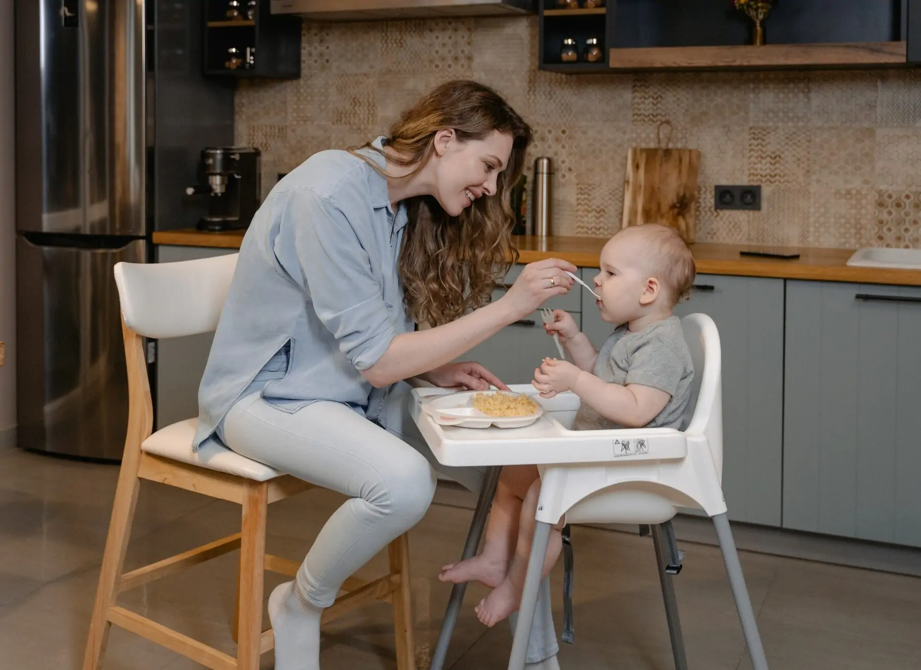 Mum feeding baby on highchair.