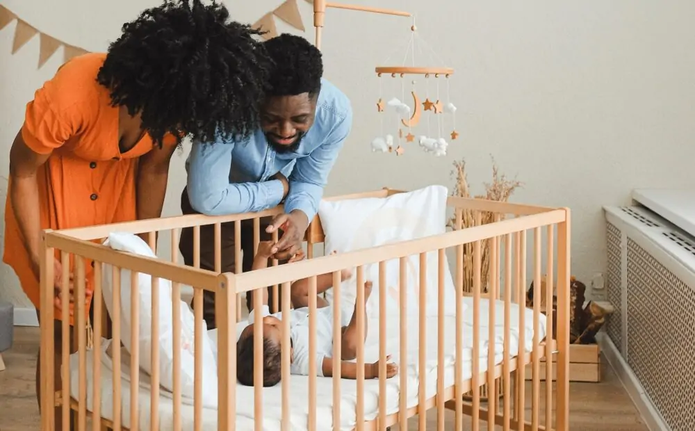 Parents with baby in cot.