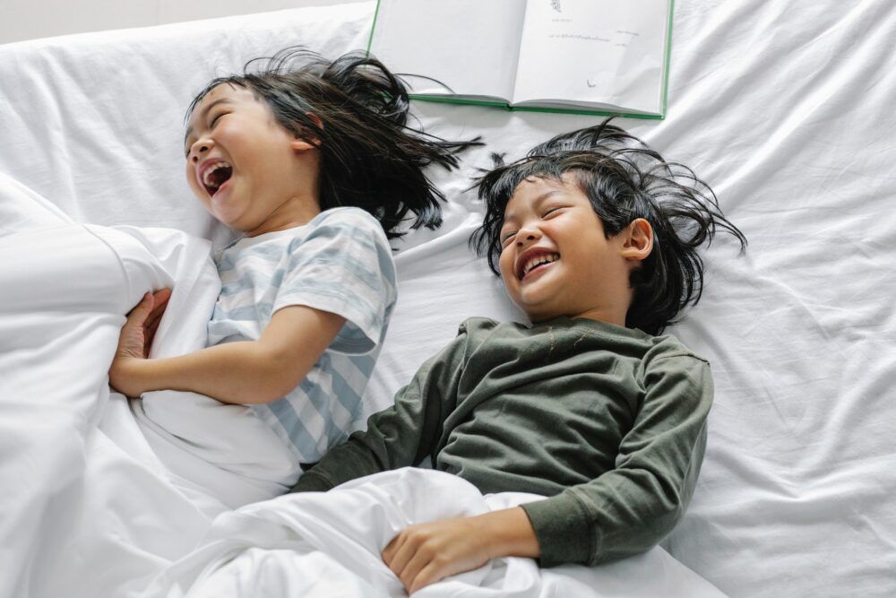 Two kids laughing in bed.