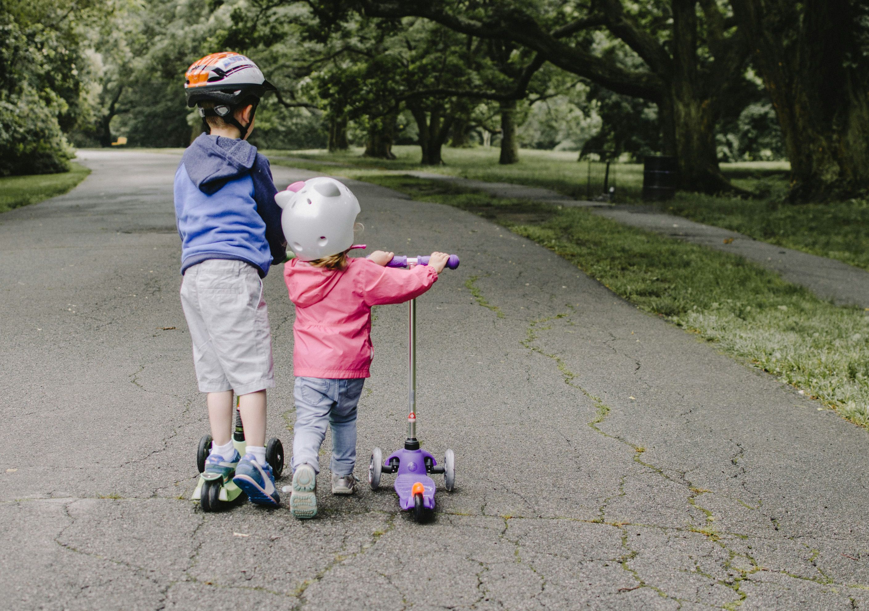 two children in a park with scooters