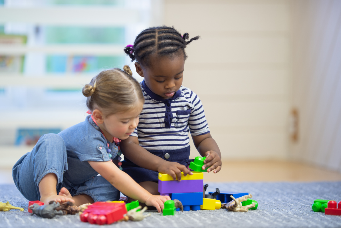 Two kids play together at home with building blocks.