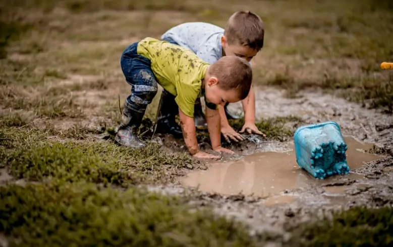 Two boys play in the mud.